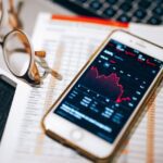 Persona consultando gráficos de bolsa en el móvil, mejores brokers para invertir en España