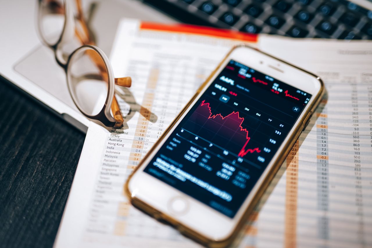Persona consultando gráficos de bolsa en el móvil, mejores brokers para invertir en España