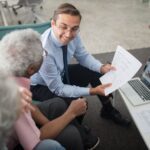 Préstamos para Pensionistas en España: Quién los Concede y Qué Condiciones Piden en 2026 Agente mostrando documentos de un préstamo a un hombre mayor