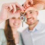 Pareja joven sosteniendo las llaves de su primera vivienda comprada con aval ICO en 2026