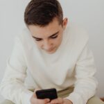 Adolescente consultando el móvil con la app de su cuenta bancaria
