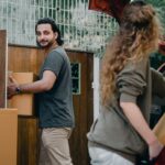 Pareja descargando cajas de mudanza en el jardín de su nueva casa