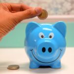 Persona introduciendo una moneda en una hucha, símbolo del ahorro para la jubilación con PIAS o plan de pensiones