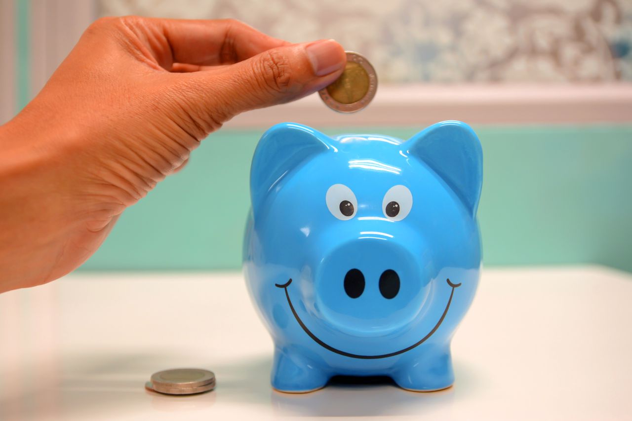 Persona introduciendo una moneda en una hucha, símbolo del ahorro para la jubilación con PIAS o plan de pensiones