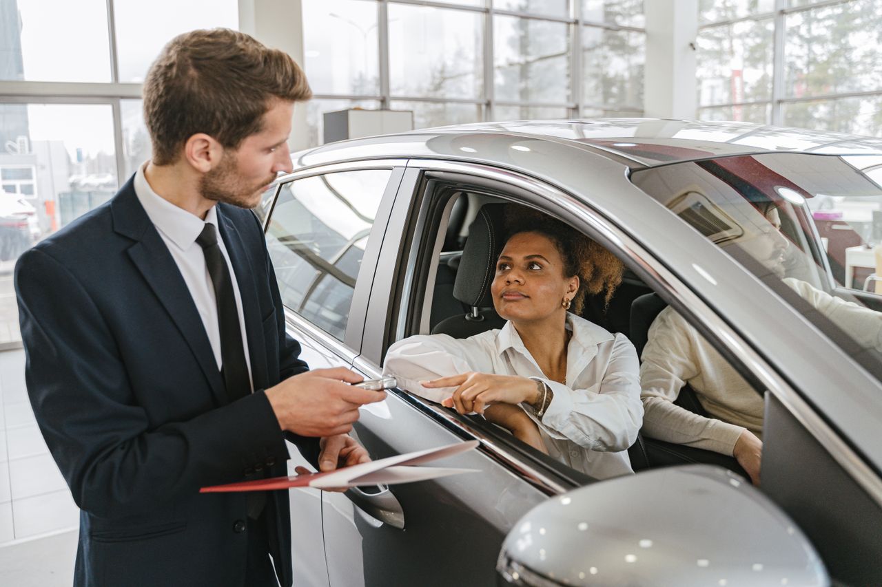Concesionario entregando las llaves de un coche nuevo a una clienta